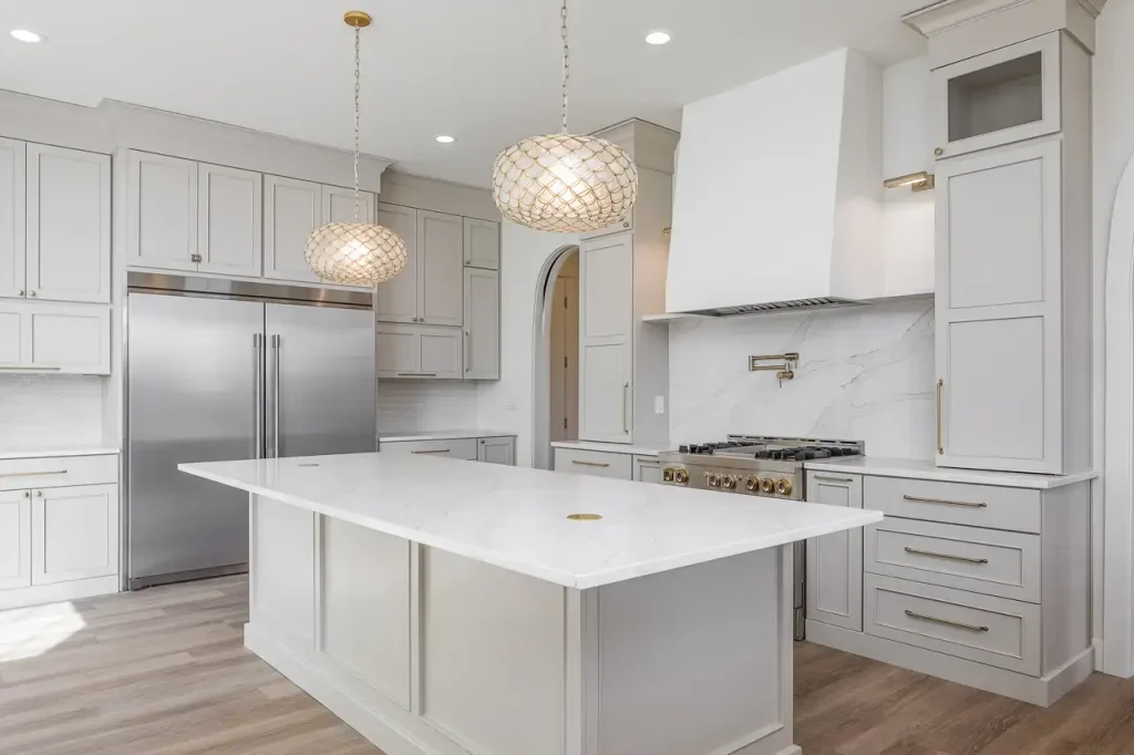 A kitchen with a decoratively designed white hood over the stove